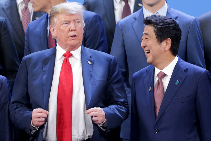 Japan’s Prime Minister (right) laughs in the vicinity of American president and unindicted co-conspirator Donald Trump on November 30, 2018 in Buenos Aires, Argentina